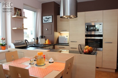 Moderní kuchyně v zemitých barvách a dekoru dřeva spojená s jídelním koutem.