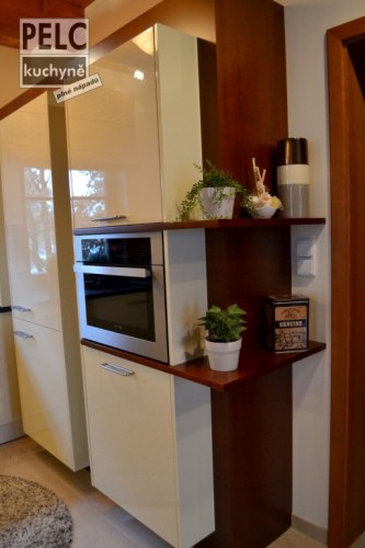 Propojení prostoru kuchyně s obývacím pokojem a předsíní pomocí opticky vsazených polic.