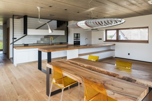 Interiér kuchyně a jídelny s výrazným prvkem masivního dřeva na desce stolu a kuchyně.