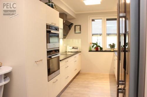 Moderní kuchyně s rovnoběžnými pracovními plochami a propojením s obývacím pokojem.